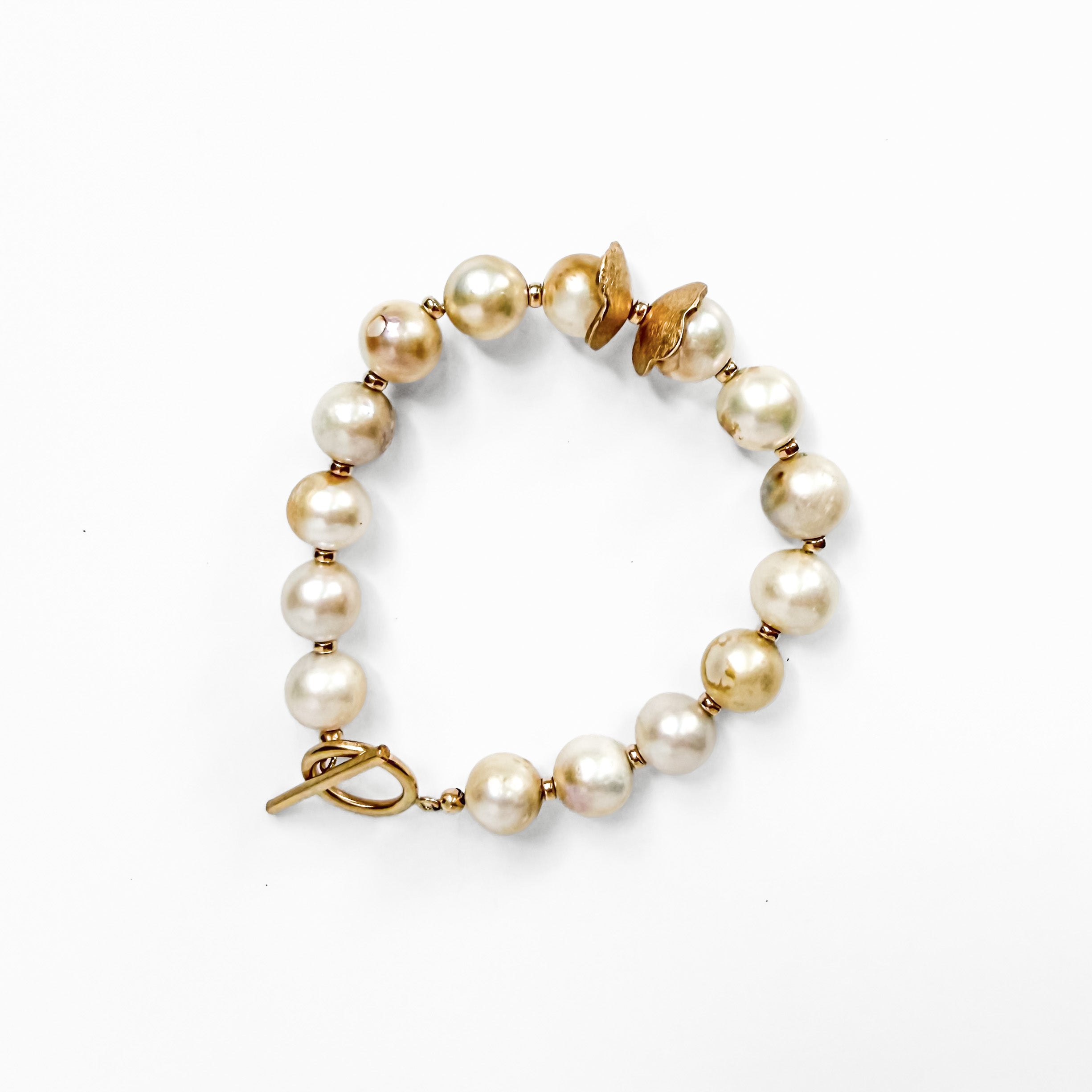 A beaded bracelet featuring irregular white freshwater pearls and gold-toned metal spacers, including a butterfly-shaped accent and a toggle clasp, shown on a plain white background.