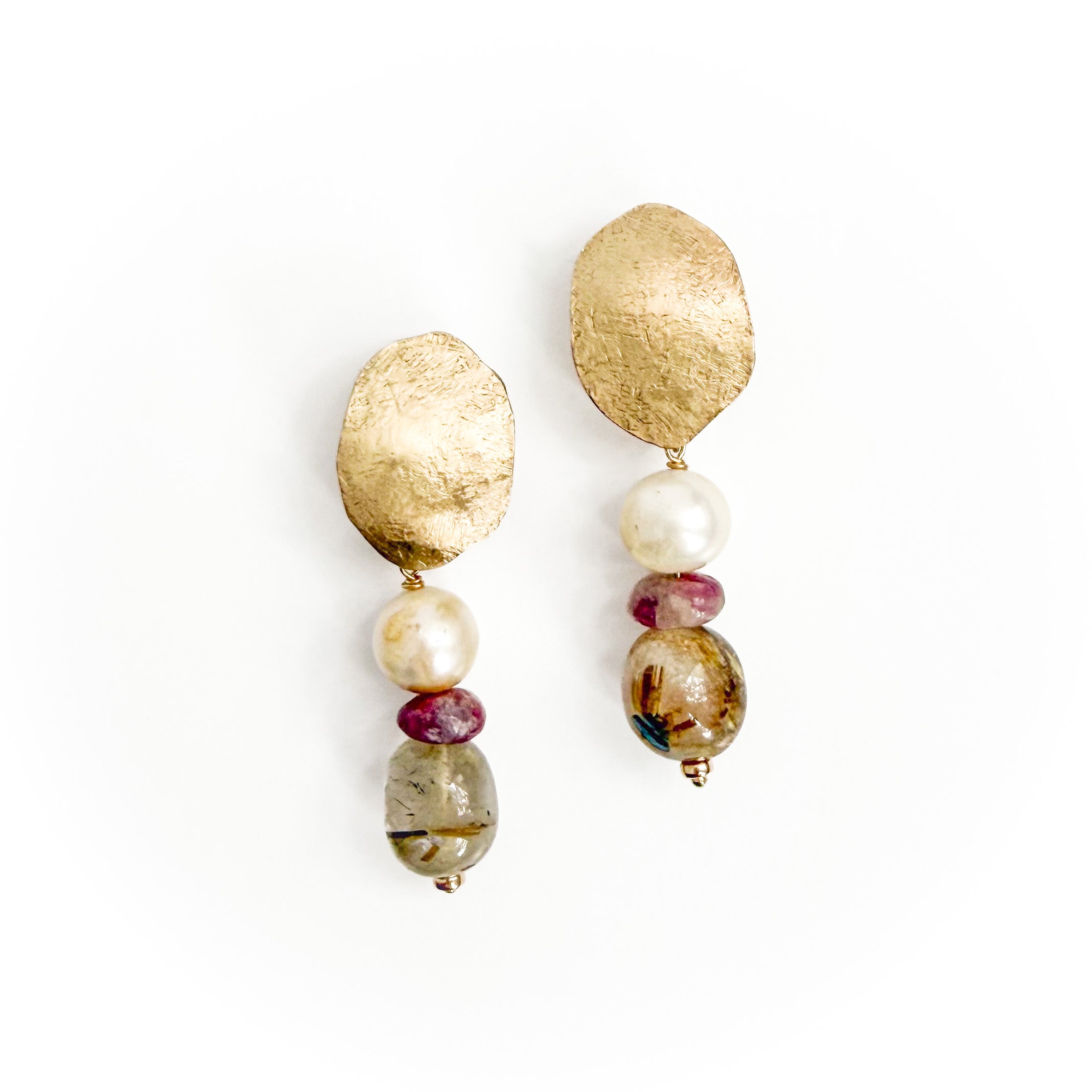 A pair of handmade dangle earrings featuring textured gold leaf discs, white faux pearls, small burgundy beads, and a larger marbled brown and gold bead, displayed on a clean white background.