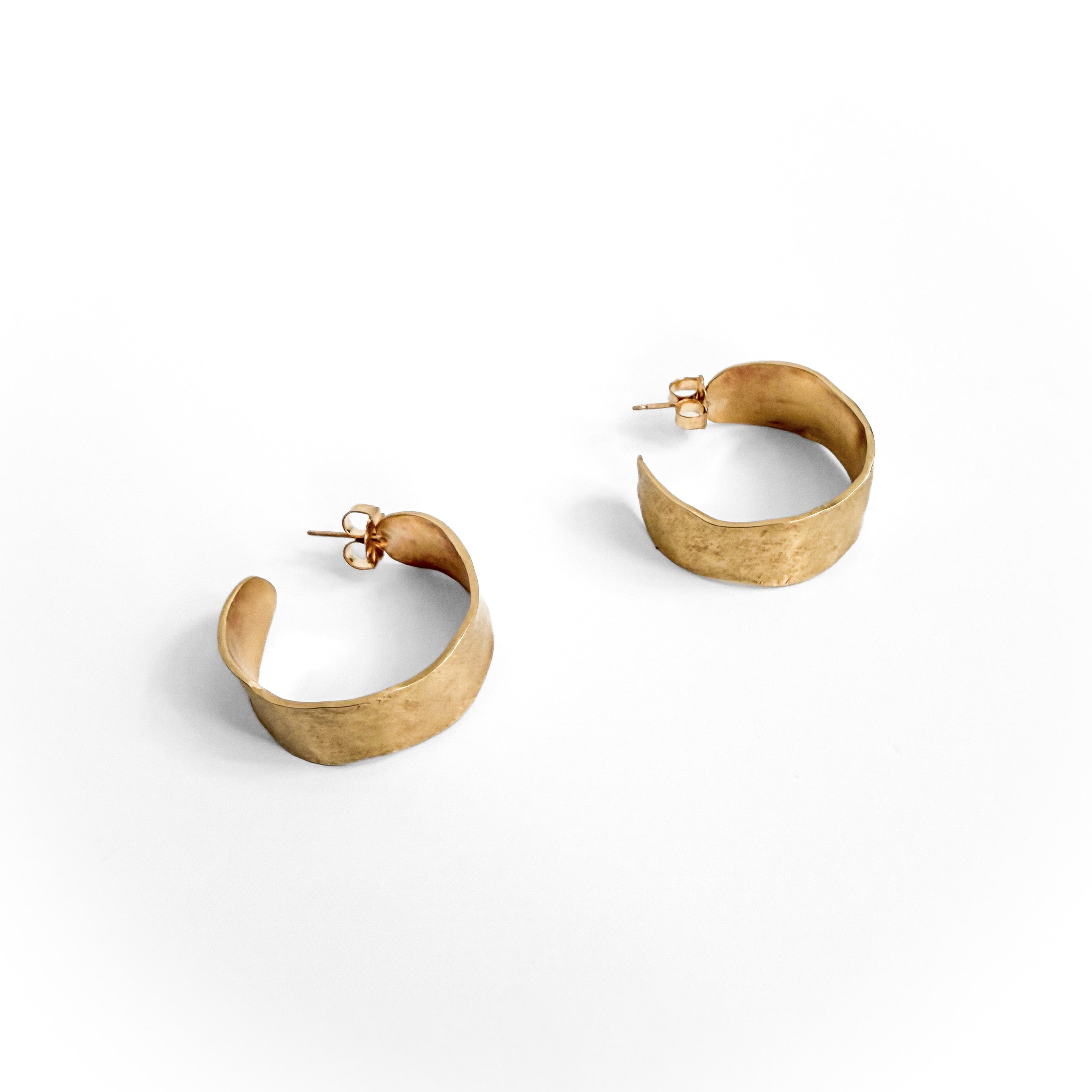 A pair of textured gold huggie hoop earrings with post-back closures, displayed on a clean white background.
