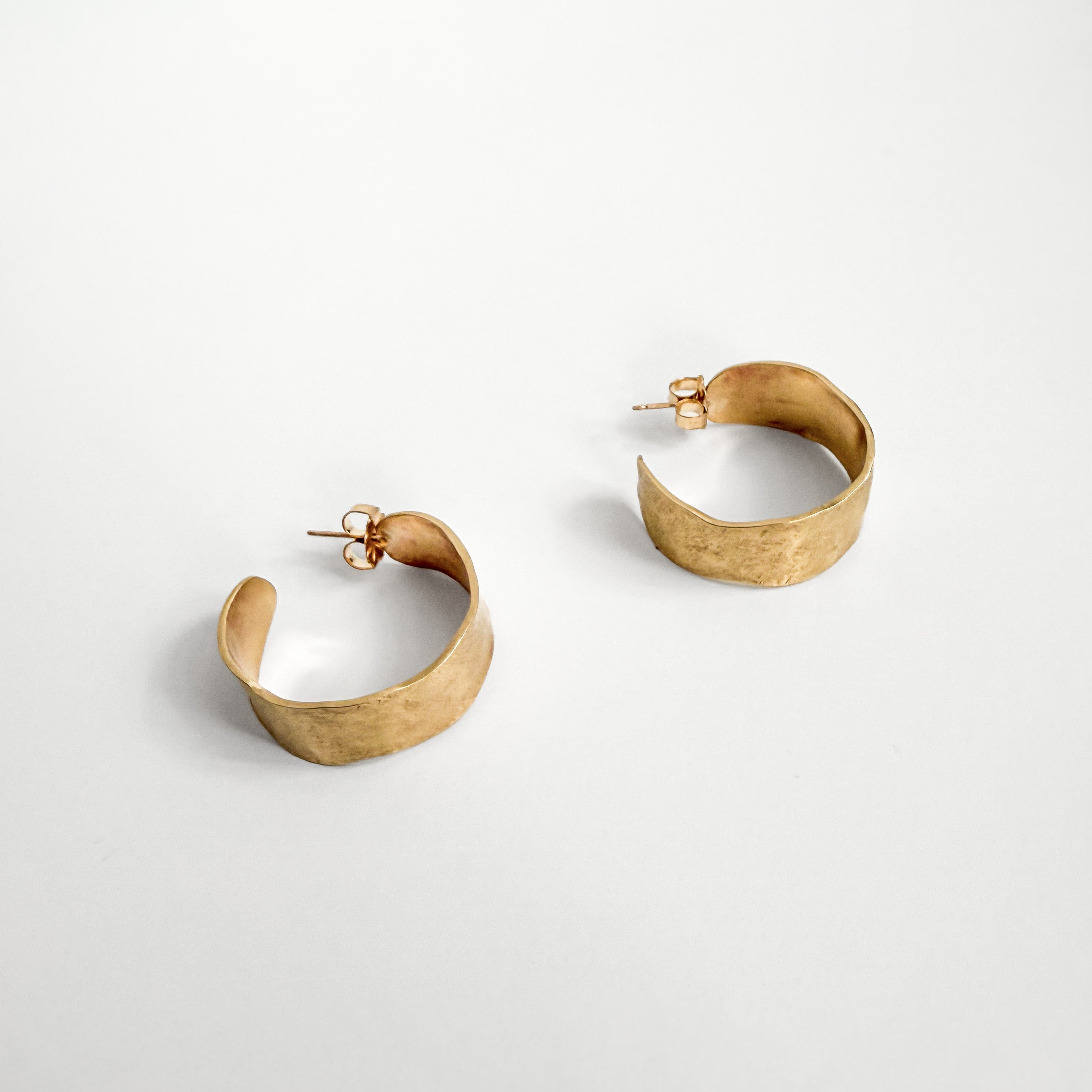 Side view of Solana brass hoop earrings showing their hand-formed curved profile