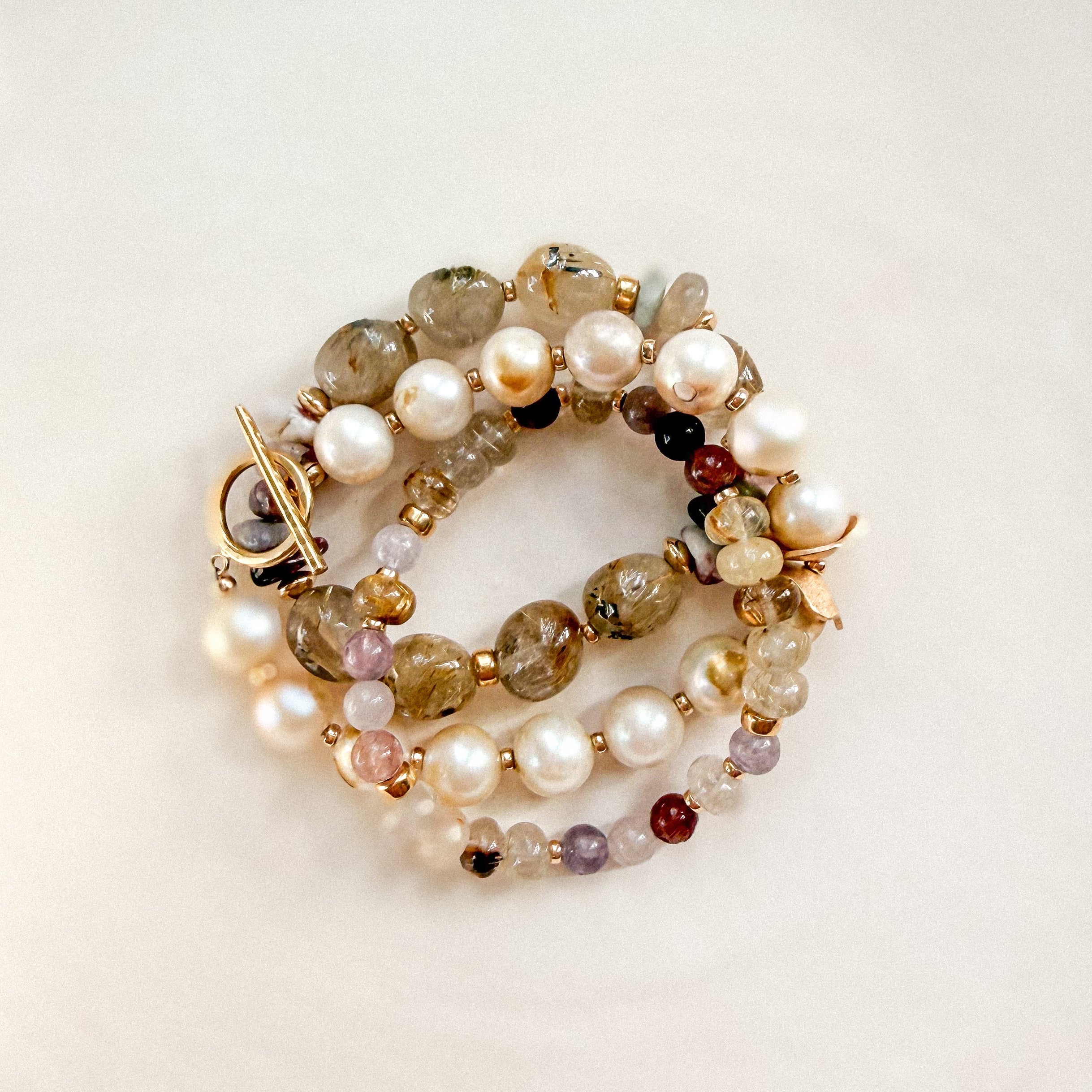 Aveline rutilated quartz and pink spinel bracelet layered with pearl and gemstone bracelets