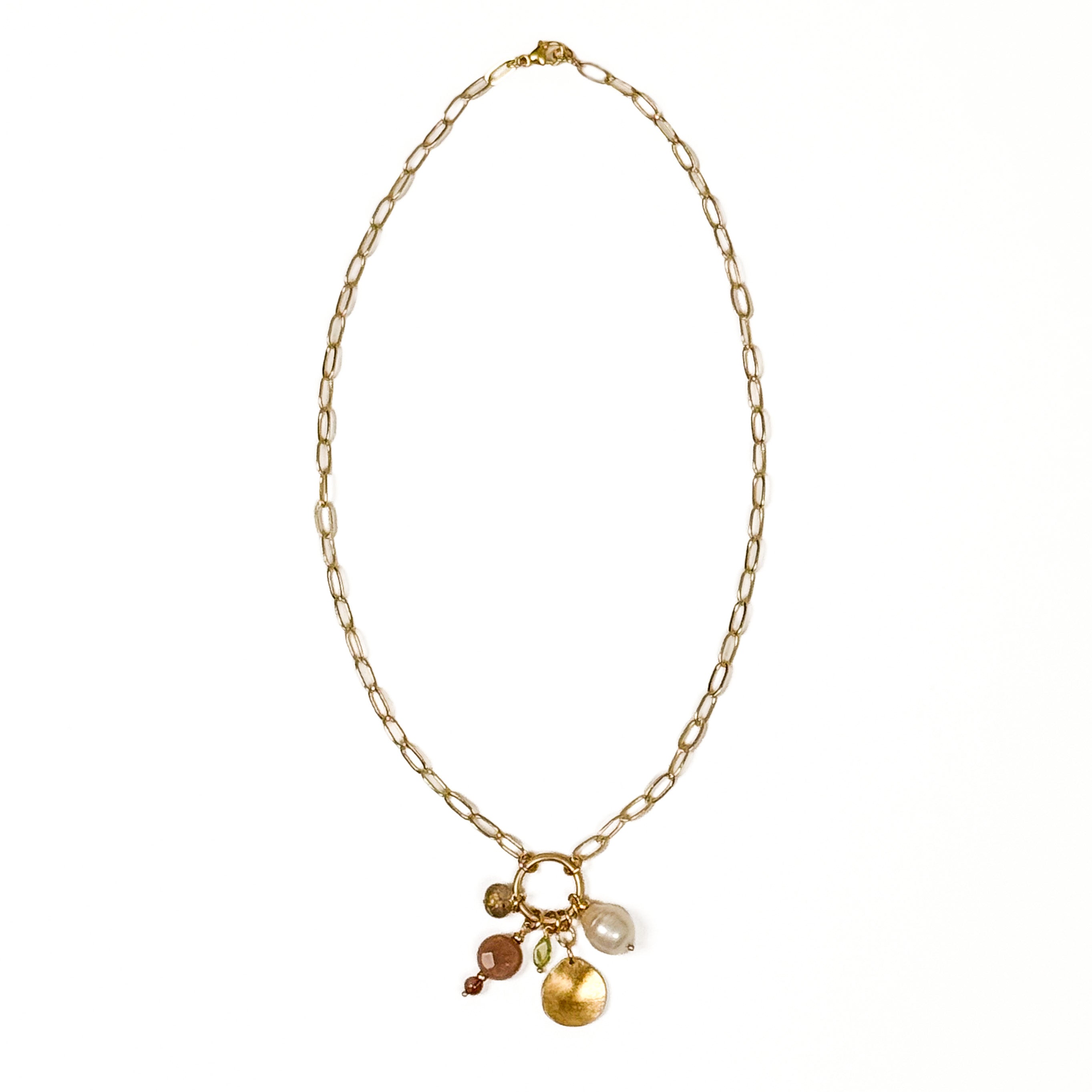 A gold-filled chain necklace with a small ring clasp holding several dangling charms, including a round gold pebble, a white pearl, a peridot, and two smaller pink beads, shown on a plain white background.