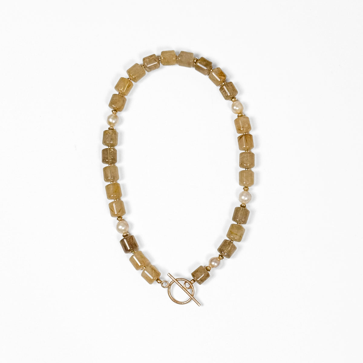 A beaded necklace featuring rectangular translucent golden rutilated quartz beads, small champagne pearls, and a gold toggle clasp, displayed on a clean white background.