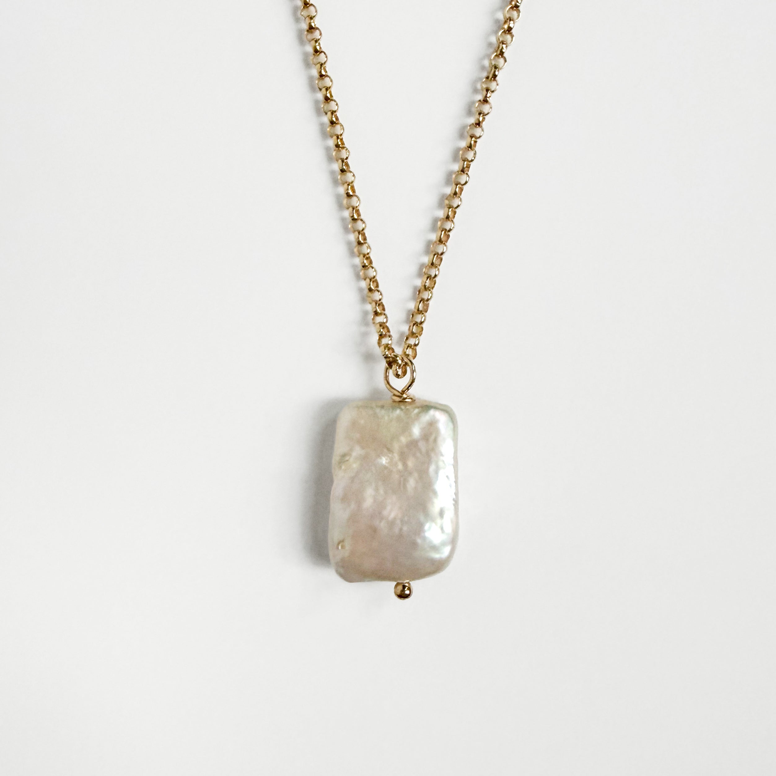 Close-up of natural rectangular Biwa freshwater pearl on gold-filled chain
