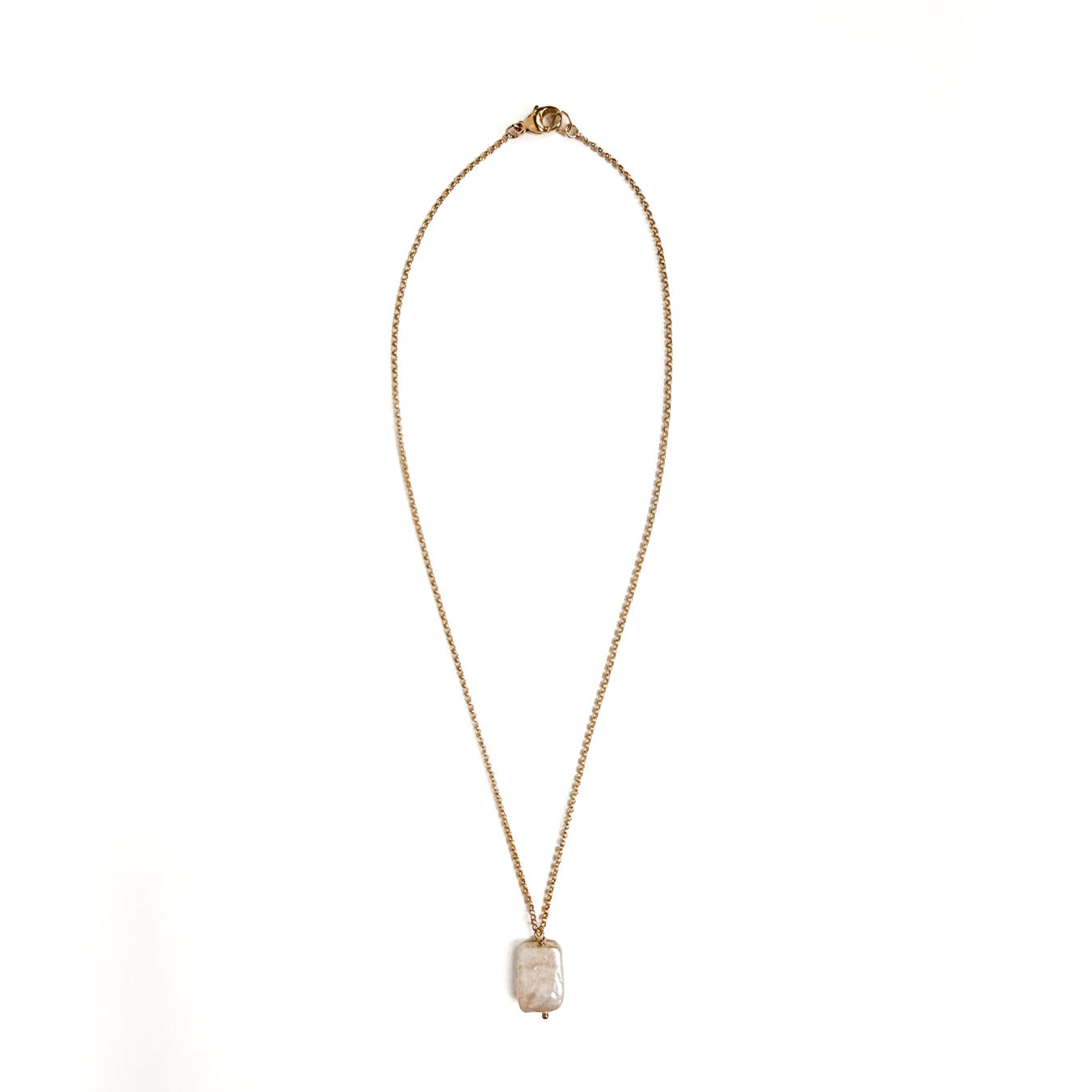 A delicate gold chain necklace with a small, rectangular, textured off-white stone pendant, displayed against a solid white background.