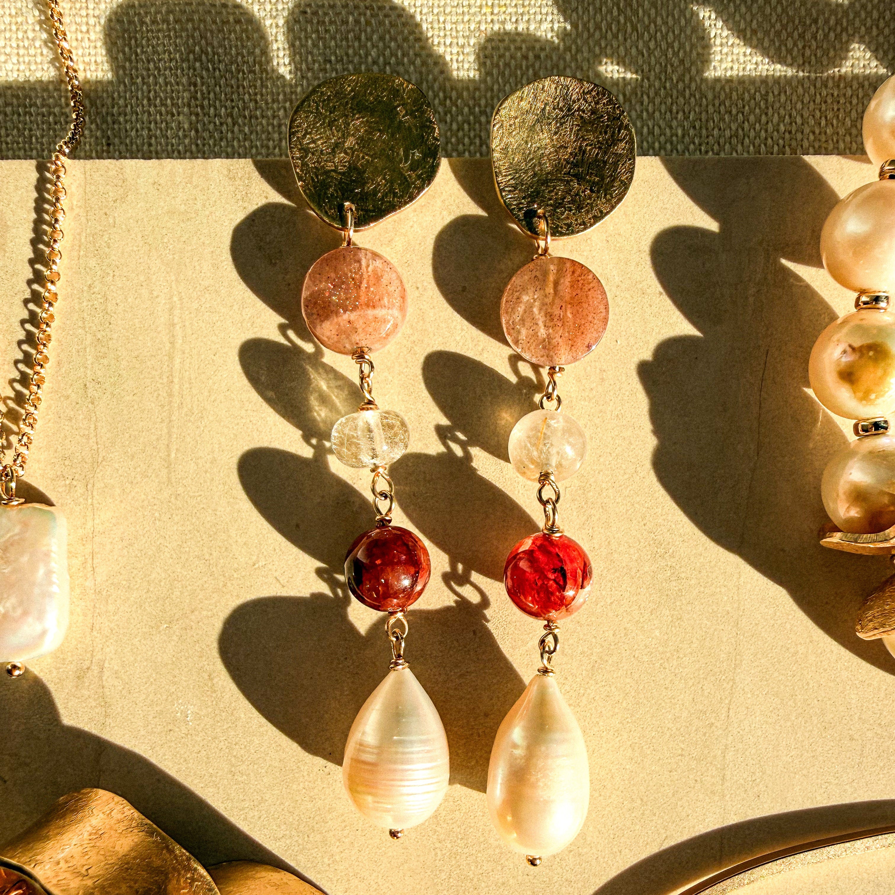 Handmade Sabine gemstone and pearl earrings with textured brass pebble studs in sunlight