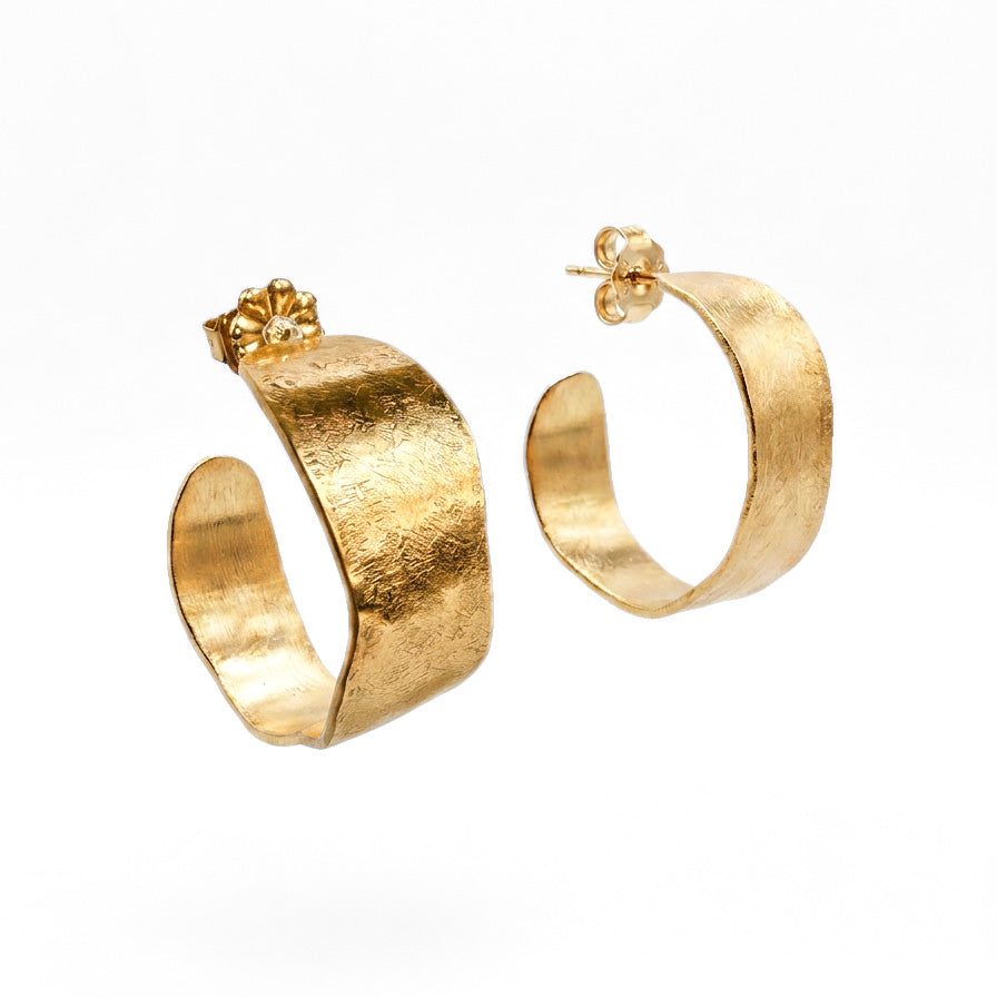 A pair of textured gold hoop earrings with a small flower-shaped stud detail, shown on a clean white background.