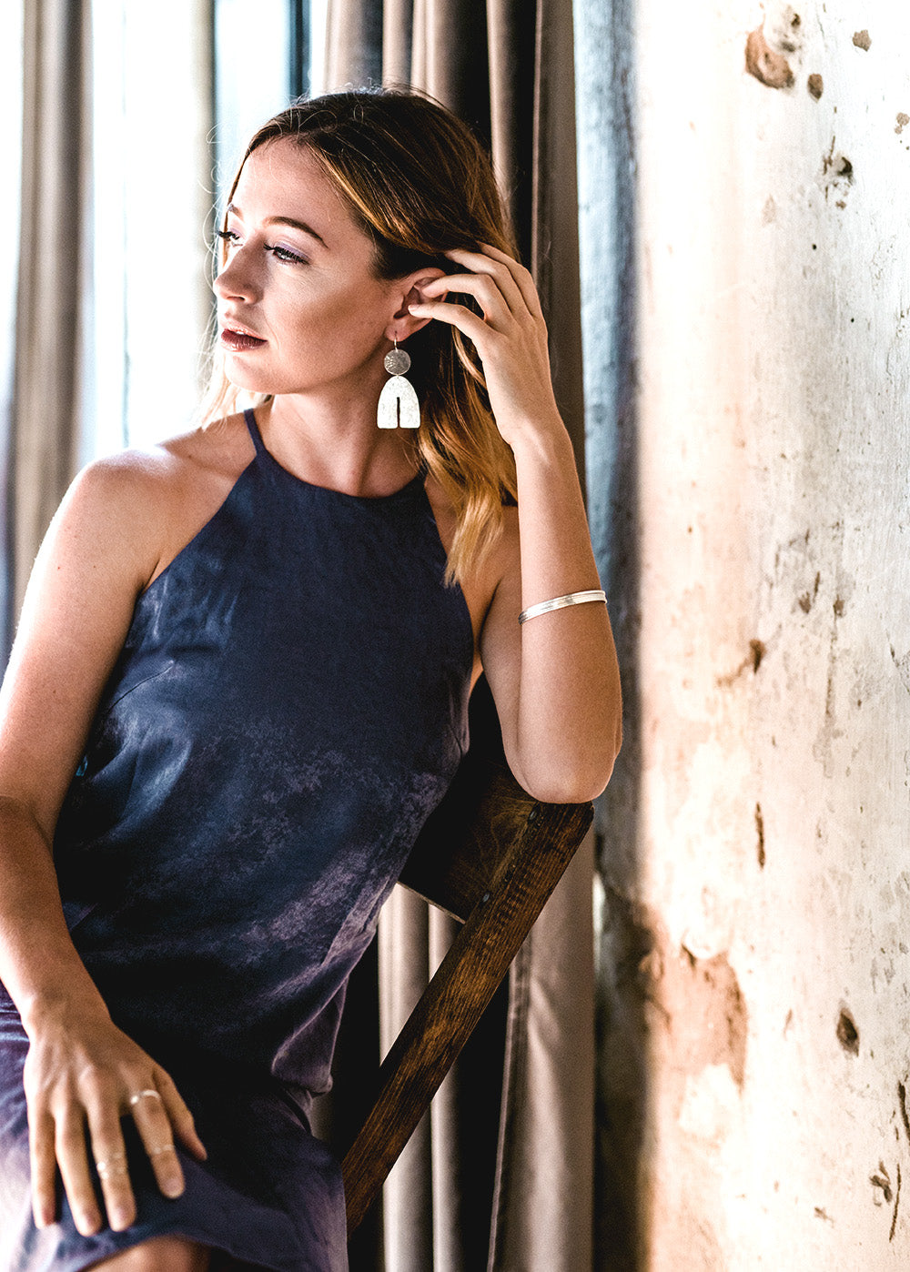 Model wearing ARCTIC sculptural arc earrings in hammered sterling silver by OH LITTLE FOXES.